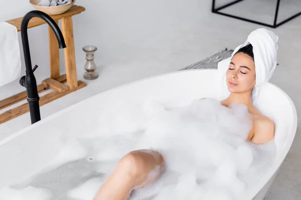 Femme relaxante avec les yeux fermés dans la baignoire moderne — Photo de stock