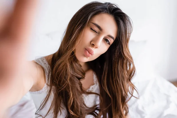Brunette woman with face expression looking at camera in bedroom — Stock Photo