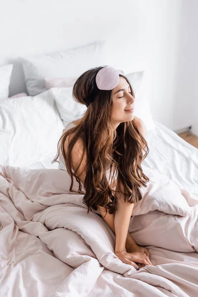 Brunette femme dans les yeux bandés assis sur le lit à la maison — Photo de stock