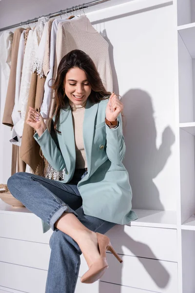 Cheerful woman looking at heeled shoe in wardrobe — Stock Photo