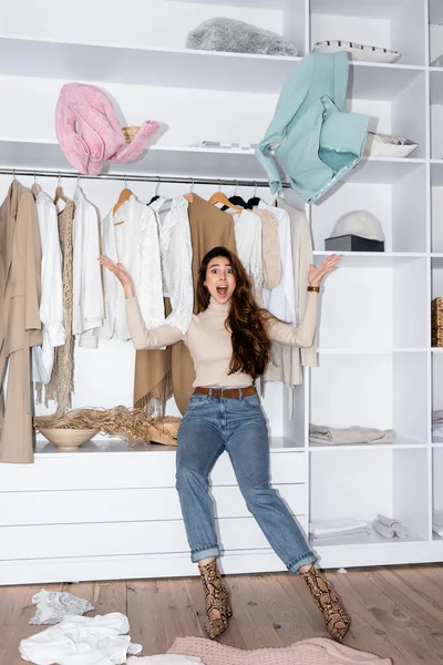 Захоплена жінка кидає одяг і дивиться на камеру в гардеробі — стокове фото