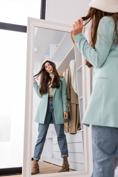 Mujer sobresaliendo de la lengua mientras mira el espejo en primer plano borroso en el armario - foto de stock
