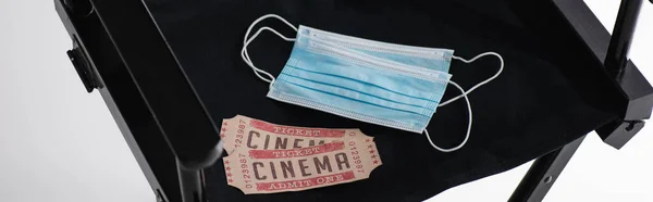 Biglietti per il cinema e maschere mediche sulla sedia del regista nero su bianco, banner — Foto stock