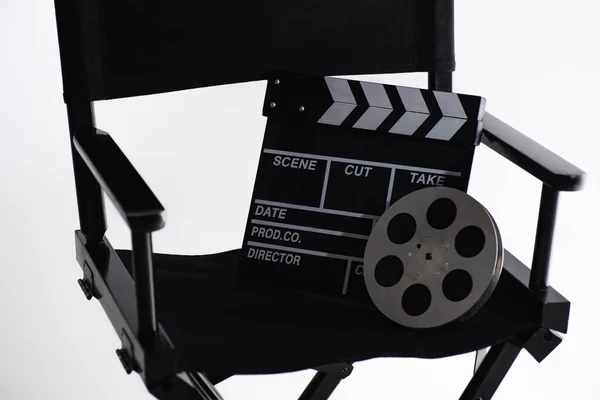 Sedia regista, clapperboard e bobina di film su bianco, concetto di cinema — Foto stock