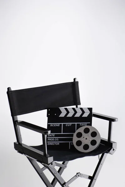 Clapperboard and film reel on director chair on white with copy space, cinema concept — Stock Photo
