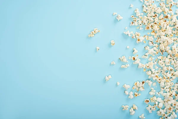 Top view of scattered crispy popcorn on blue, cinema concept — Stock Photo