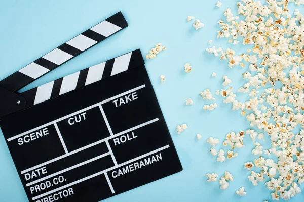 Top view of clapperboard near popcorn scattered on blue, cinema concept — Stock Photo