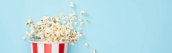 Top view of paper bucket with crunchy popcorn on blue, banner, cinema concept — Stock Photo