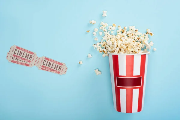 Vista dall'alto del secchio con gustosi popcorn vicino ai biglietti del cinema sul blu — Foto stock