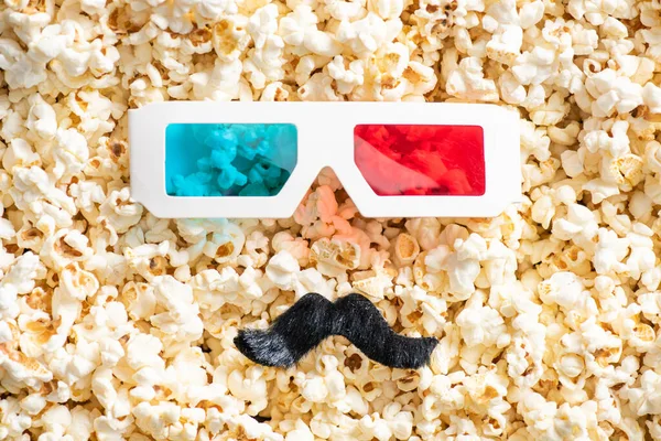 Top view of 3d glasses and artificial mustache on scattered popcorn, cinema concept — Stock Photo