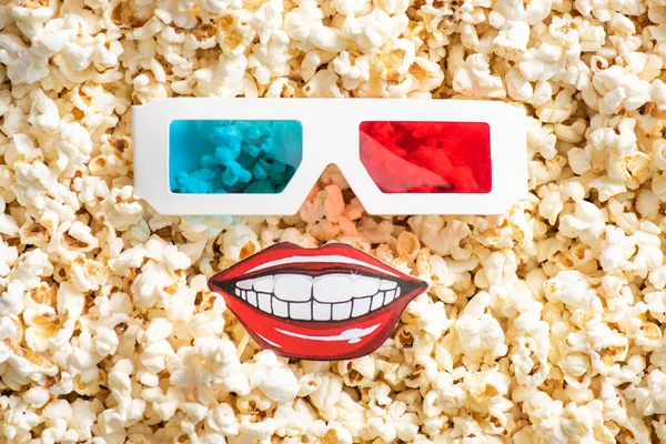 Top view of 3d glasses and paper cut smiling mouth on crispy popcorn, cinema concept — Stock Photo