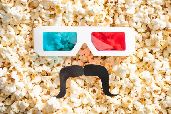 Vista superior de gafas 3d y bigote de corte de papel en palomitas de maíz sabrosas dispersas, concepto de cine — Stock Photo
