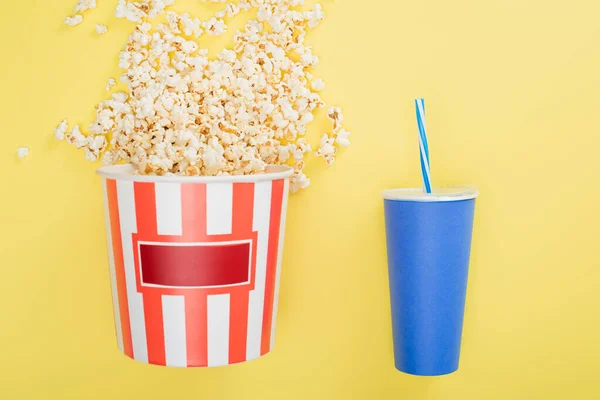 Balde de pipoca perto de xícara de refrigerante em amarelo, conceito de cinema — Fotografia de Stock