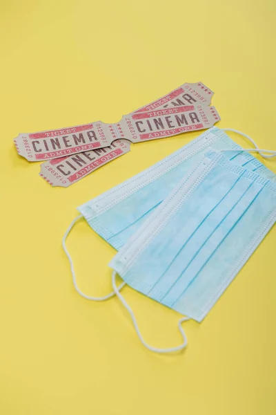 Biglietti del cinema vicino a maschere mediche su giallo, concetto di cinema — Foto stock