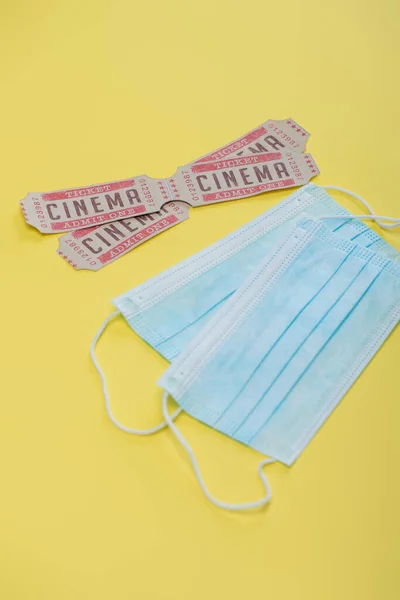 Billets de cinéma près de masques médicaux sur jaune, concept cinéma — Photo de stock