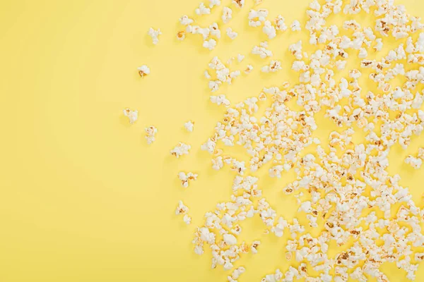 Vue de dessus du pop-corn croquant éparpillé sur jaune, concept de cinéma — Photo de stock