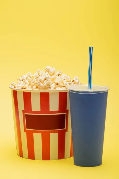 Cup of soda near bucket full of tasty popcorn on yellow, cinema concept — Stock Photo