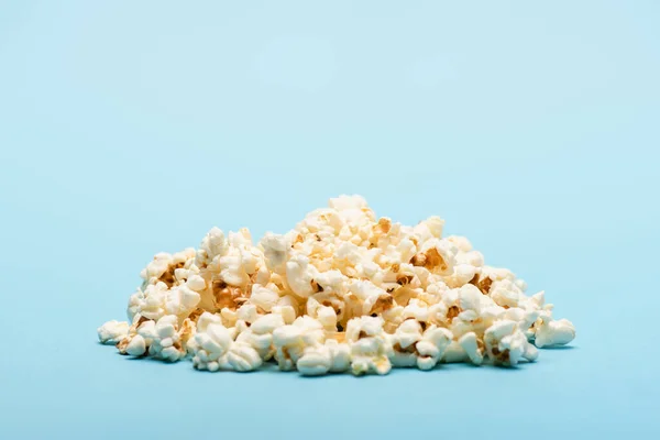 Pile of crunchy airy popcorn on blue with copy space, cinema concept — Stock Photo