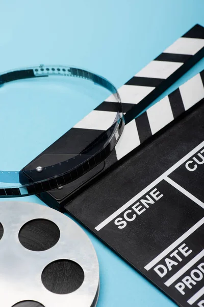 Vue rapprochée de bobine de film et clapperboard sur bleu, concept de cinéma — Photo de stock