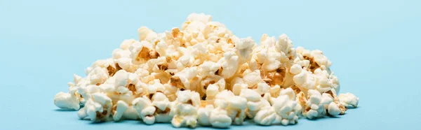 Pile of tasty salty popcorn on blue, banner, cinema concept — Stock Photo