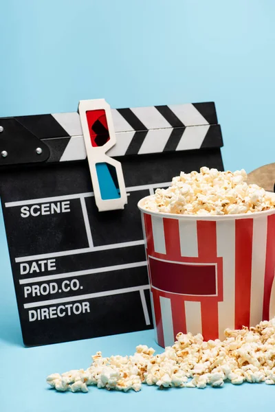 Klappbrett, 3D-Brille und Eimer mit leckerem Popcorn auf Blau, Kinokonzept — Stockfoto