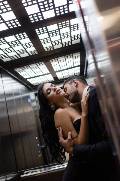 Jovem beijando mulher sensual perto do espelho no elevador — Fotografia de Stock