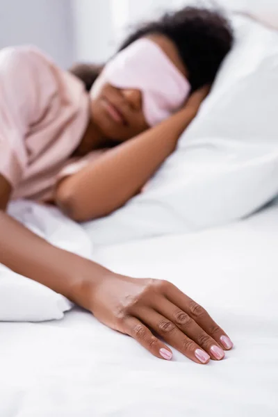 Mano di donna afro-americana che dorme su biancheria da letto bianca su sfondo sfocato — Foto stock
