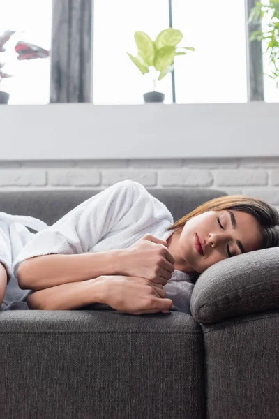 Mujer adulta joven durmiendo en el sofá gris en casa — Stock Photo