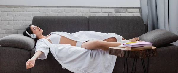 Mujer adulta joven durmiendo en auriculares en el sofá en casa, pancarta - foto de stock