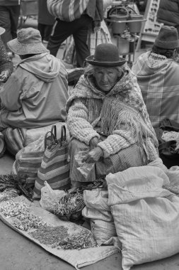 ORURO, BOLIVIA - 24 Şubat 2017: Bolivya 'nın Altiplano kentindeki Oruro madencilik şehrinde çiçek kafası satan melon şapkalı yaşlı kadın.