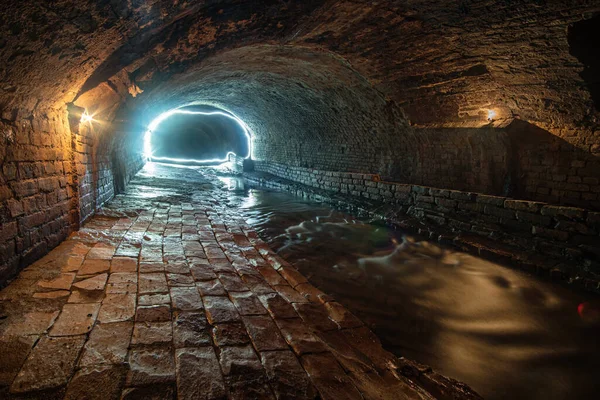 Tunel Starego Kanalizacji Ceglanej Ciepłym Światłem Pierwszym Planie Zimnem Tle — Zdjęcie stockowe