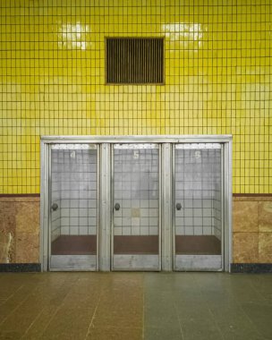 Sarı seramik kiremitleri olan renkli desenli bir duvar çelik takılı cam kapılar ve pirinç havalandırma ızgarası. 1960 'ların tarzında mimari.