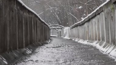 Beton bir hendekte bir dere ya da ormanda kışın yağmur suyu kanalı. Kışlık ormanda temiz suyla fırtına drenajı.