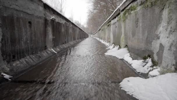 Un arroyo en una zanja de hormigón o canal de agua de lluvia en invierno en el bosque. Drenaje de tormentas en bosque invernal con agua clara. — Vídeo de stock