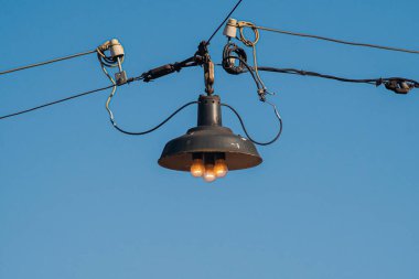 Mavi gökyüzünün arka planında üç tungsten lambası olan eski model sokak lambası..