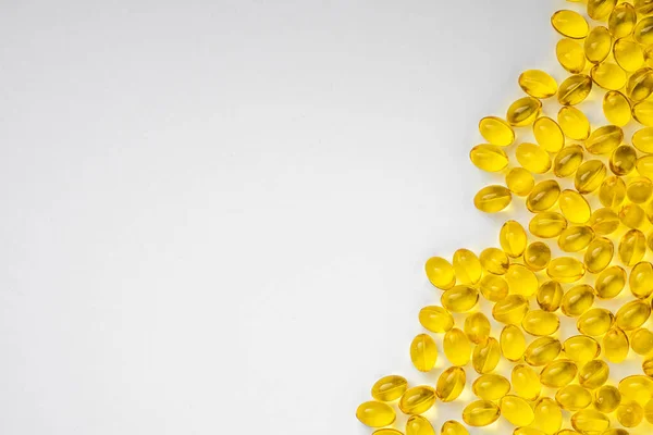 Beyaz arka planda sarı şeffaf haplar ve bir kopya alanı kalmış. D3 vitaminli haplar.