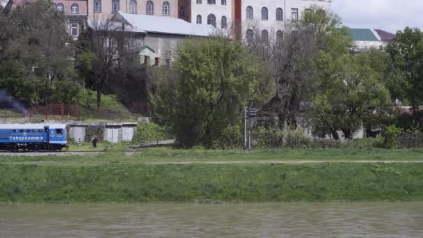 El tren azul del Ferrocarril Infantil de Uzhhorod corre en un día soleado en el terraplén del río. — Vídeo de stock
