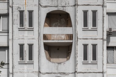 Textured shabby concrete wall with decorative windows of multi storey residential house.