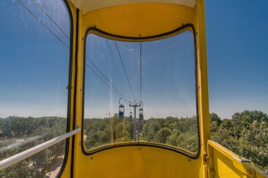 Parkta güneşli bir yaz gününde eski bir teleferiğin sarı kulübesinden ilk gören kişi..