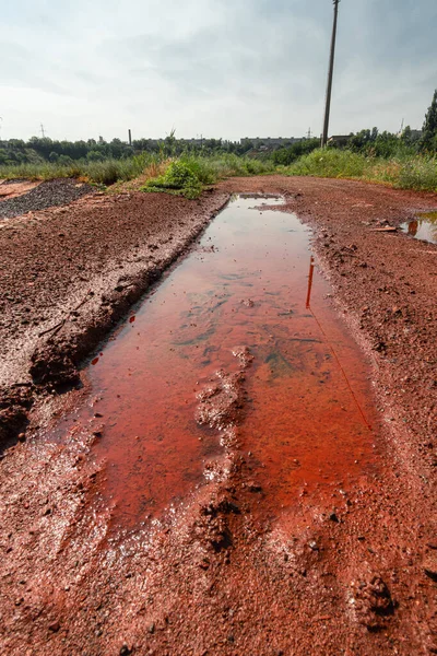 Pit with a puddle in red mud from iron ore.