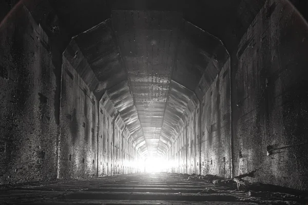 Empty abandoned railway dark tunnel with light in the end.