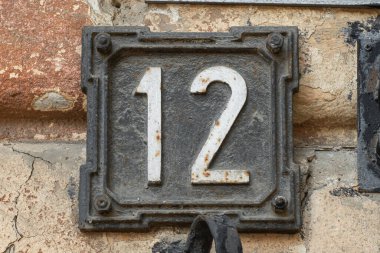 Dekoratif çelik çerçeveli beyaz 12 numara, eski bir evin ön cephesinde klasik ev numarası..