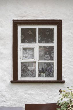 Dantel perdelerle süslenmiş eski, basit bir ahşap penceresi olan beyaz alçılı bir duvar. Geleneksel kırsal mimari. Pereyaslav, Ukrayna, 13 Eylül 2025.