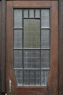 Koyu çerçeveli ve desenli cam panelleri olan klasik ahşap kapı..