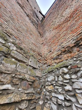 Eski kırmızı tuğla ve gri kireçtaşı duvar yeşil yosunlu..