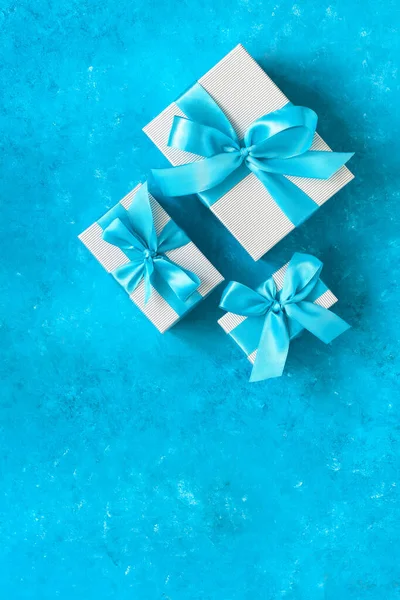 Gift boxes with blue ribbon. Turquoise blue grunge background. Top view, flat lay, copy space