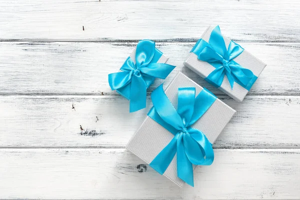 Gift boxes with blue ribbon on a white wooden background. Top view, flat lay