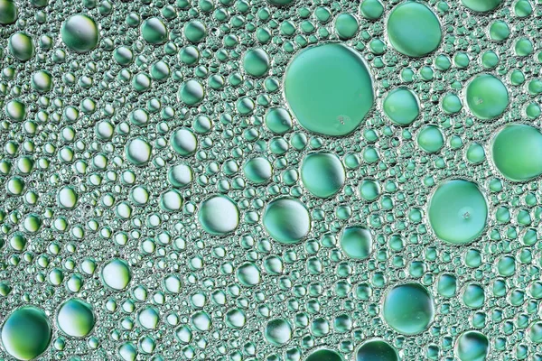 Abstract green background from drops of oil and water. Beautiful macro art background for your design