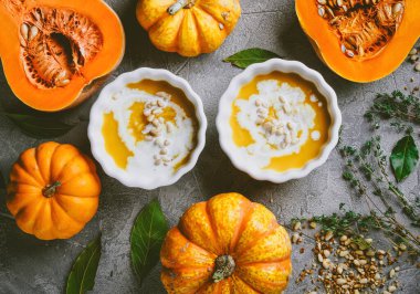 Balkabağı çorbası, balkabaklarıyla gri bir zemin üzerinde sonbahar atmosferi, üst manzara, seçici odaklanma. 