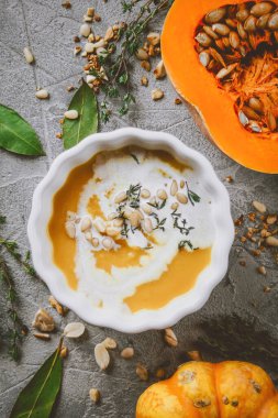 Balkabağı çorbası, balkabaklarıyla gri bir zemin üzerinde sonbahar atmosferi, üst manzara, seçici odaklanma. 